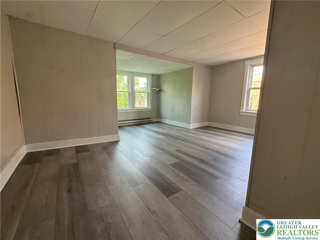 a view of an empty room with wooden floor and a window