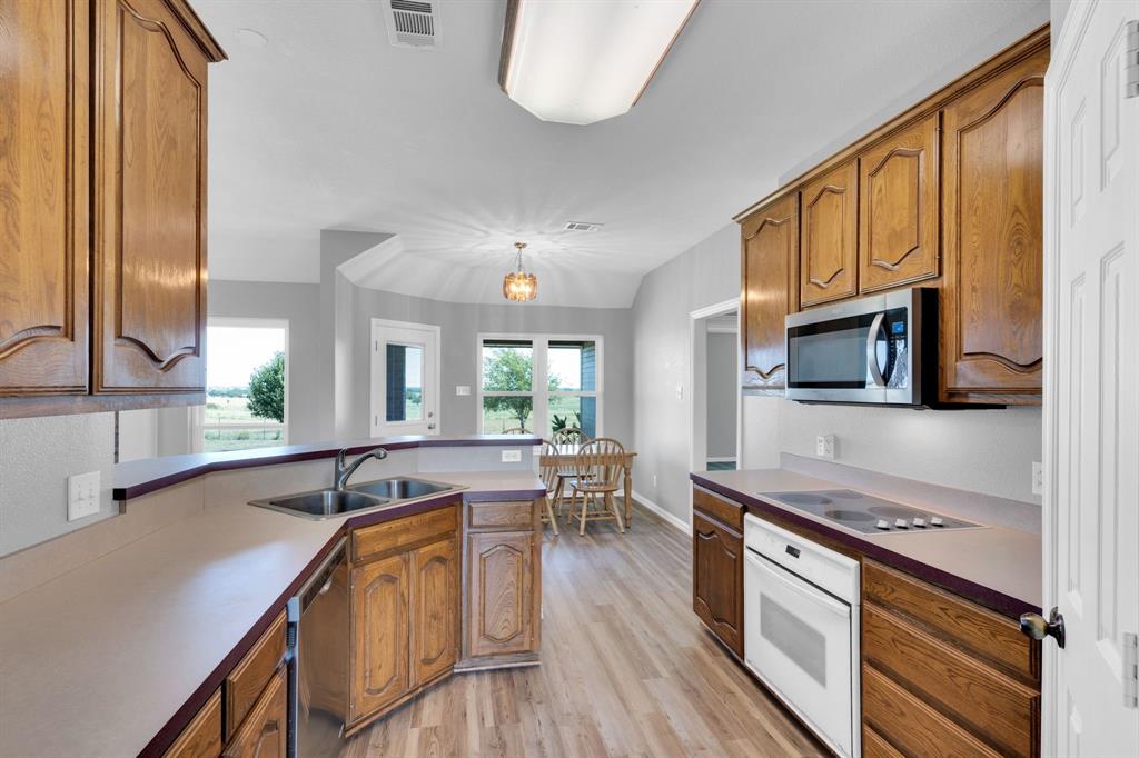 154 Richard Road Waxahachie, TX 75167 - Photo 24 of 38 a kitchen with stainless steel appliances granite countertop a sink stove and wooden cabinets