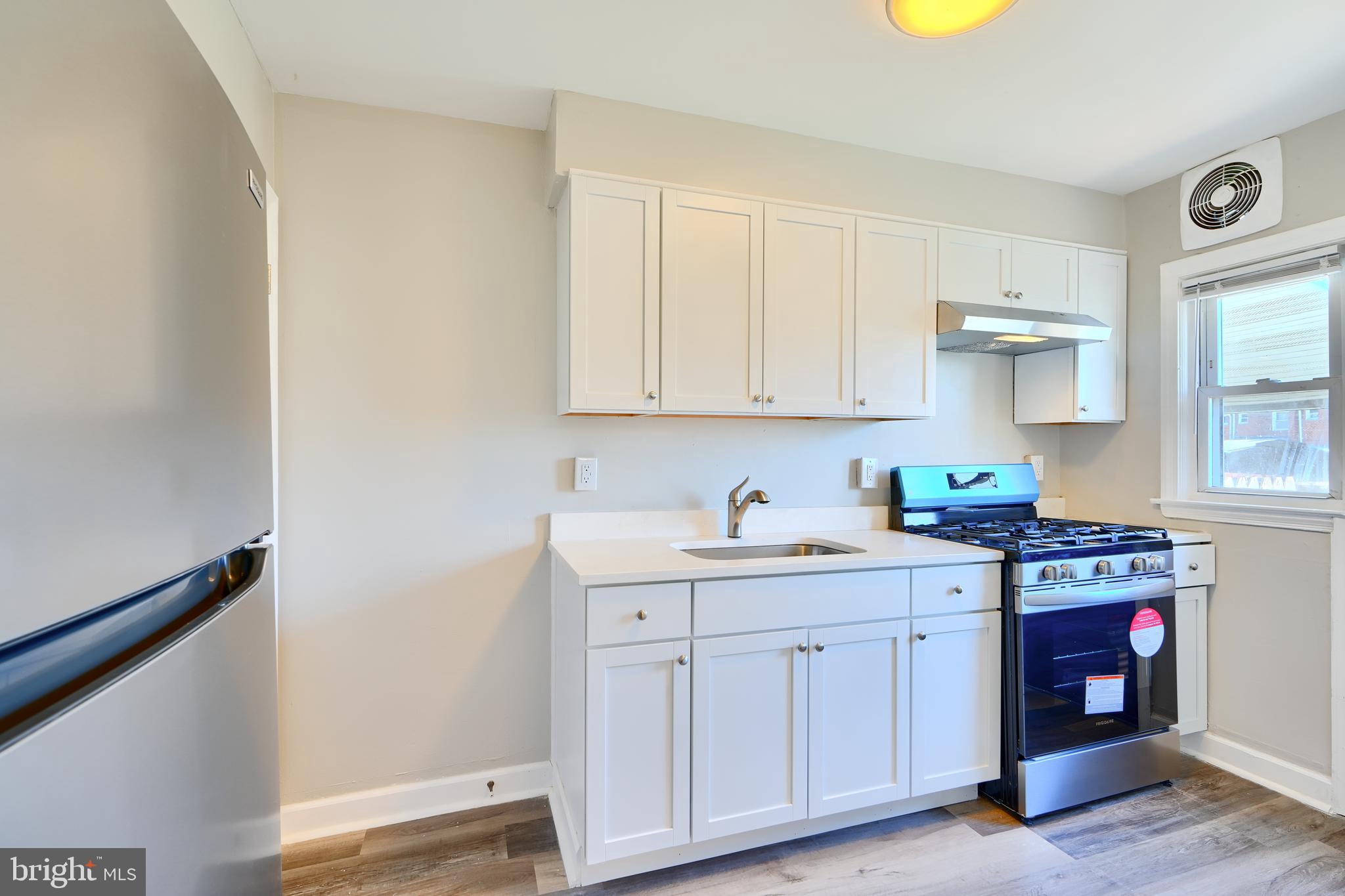 406 Torner Road Baltimore, MD 21221 - Photo 11 of 35 a kitchen with stainless steel appliances granite countertop a stove a sink and white cabinets with wooden floor
