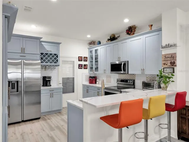 a kitchen with stainless steel appliances granite countertop a refrigerator a stove a sink dishwasher and a oven with wooden floor