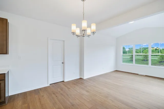 a view of a room with wooden floor chandelier and windows