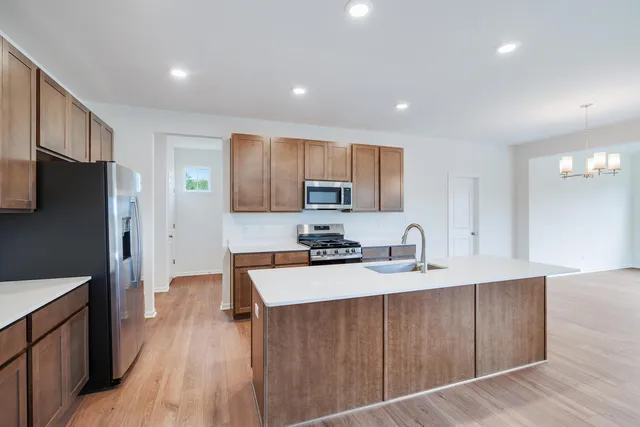 a kitchen with stainless steel appliances granite countertop a refrigerator a sink dishwasher a stove with wooden floors and cabinets