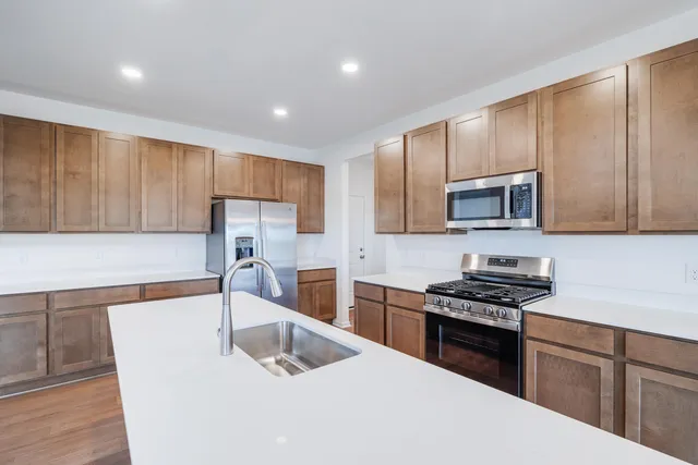 a kitchen with granite countertop a sink a stove a refrigerator cabinets and a counter top space