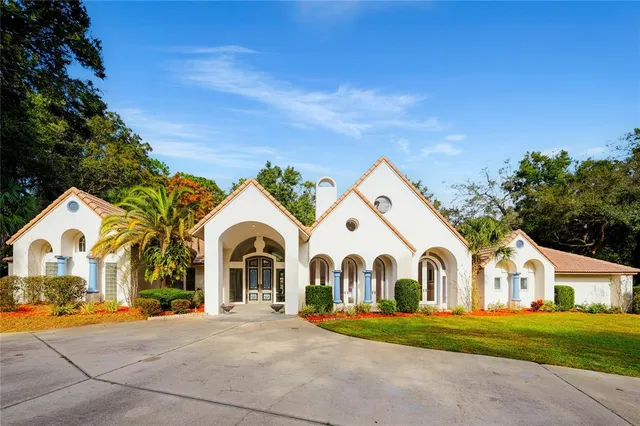 a view of white house with a big yard and large trees