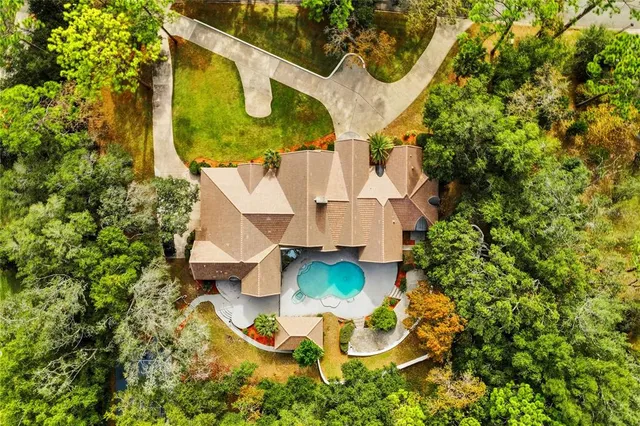 an aerial view of a house with yard and swimming pool