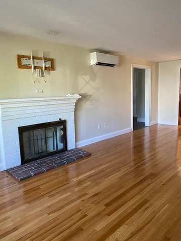 a view of empty room with wooden floor and fireplace