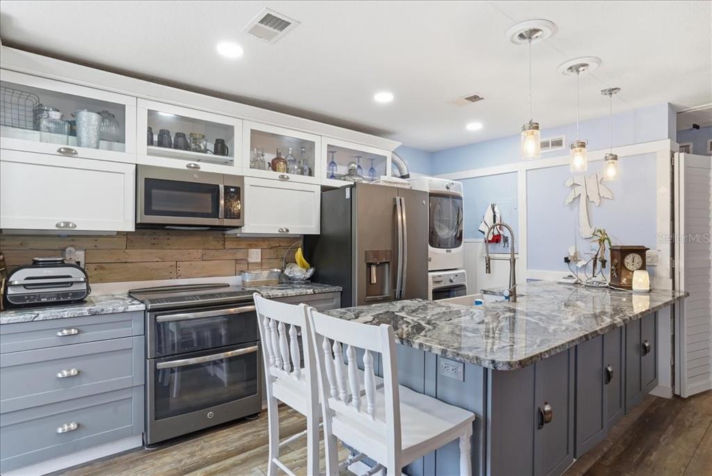 8931 Blind Pass Road, Unit 360 St. Pete Beach, FL 33706 - Photo 4 of 20 a kitchen with stainless steel appliances granite countertop a kitchen island hardwood floor and a sink
