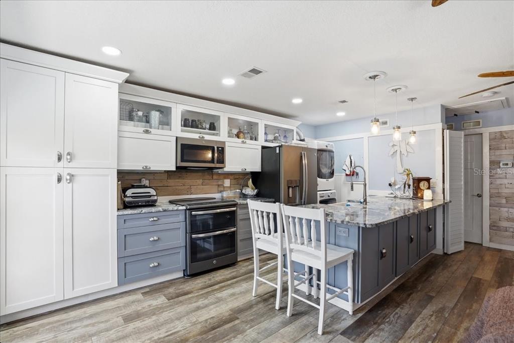 8931 Blind Pass Road, Unit 360 St. Pete Beach, FL 33706 - Photo 7 of 20 a kitchen with stainless steel appliances kitchen island granite countertop a table chairs refrigerator and a sink