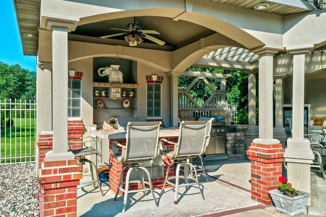 a view of a patio with table and chairs potted plants and floor to ceiling window