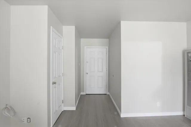 an empty room with wooden floor chandelier fan and windows