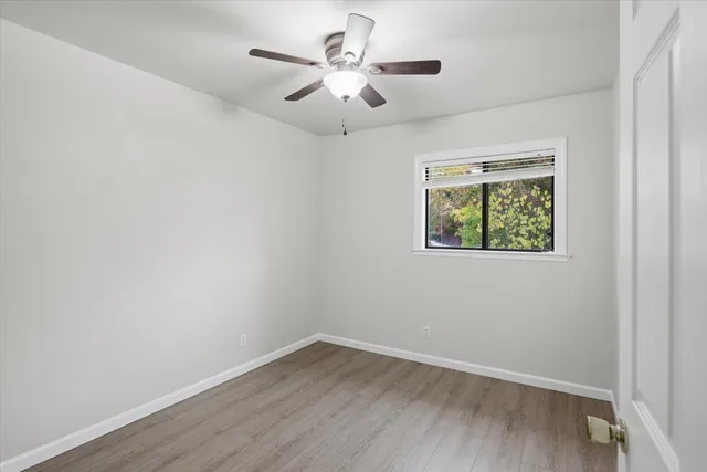 an empty room with wooden floor and ceiling fan