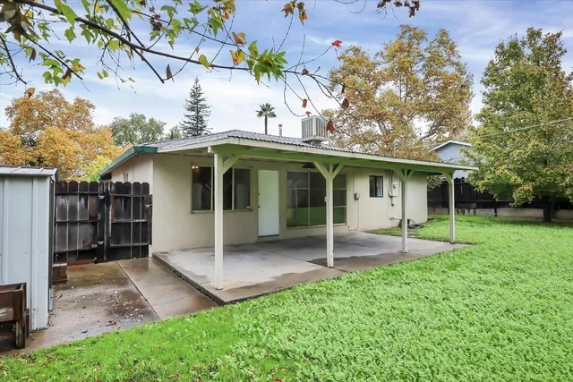 a view of a big house with a big yard plants and large trees