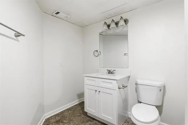 a bathroom with a toilet sink vanity and mirror