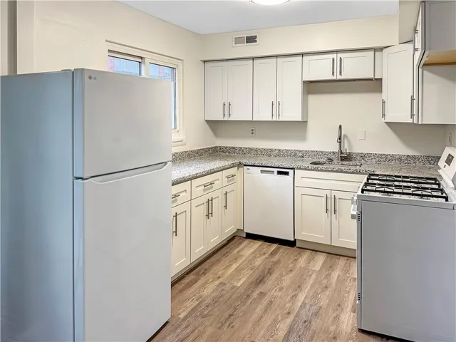 a white kitchen with a sink and white stainless steel appliances