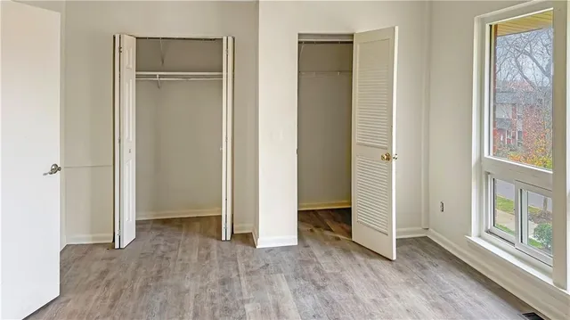 an empty room with wooden floor closet and windows