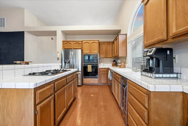 a large kitchen with stainless steel appliances granite countertop a stove top oven a sink dishwasher and cabinets with wooden floor