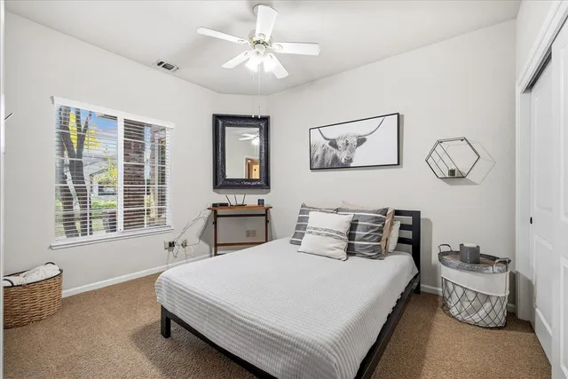 a spacious bedroom with a bed a painting on the wall and a window