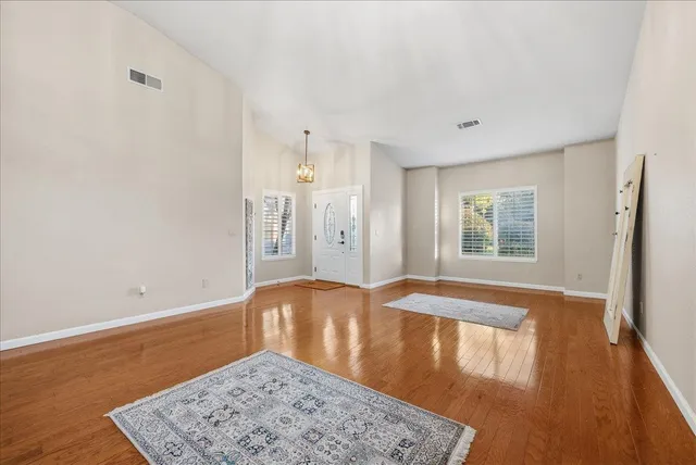 a view of an empty room with window and wooden floor
