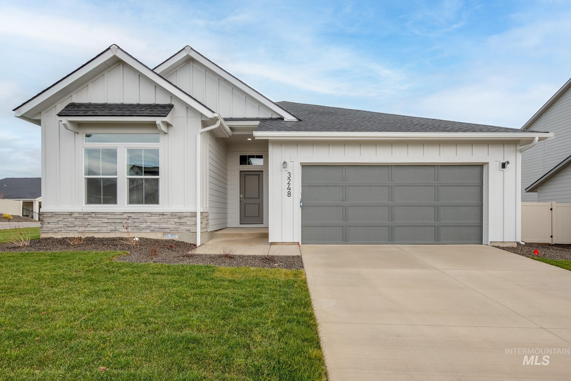 View of front facade featuring board and batten siding, roof with shingles, driveway, a front yard, and an attached garage