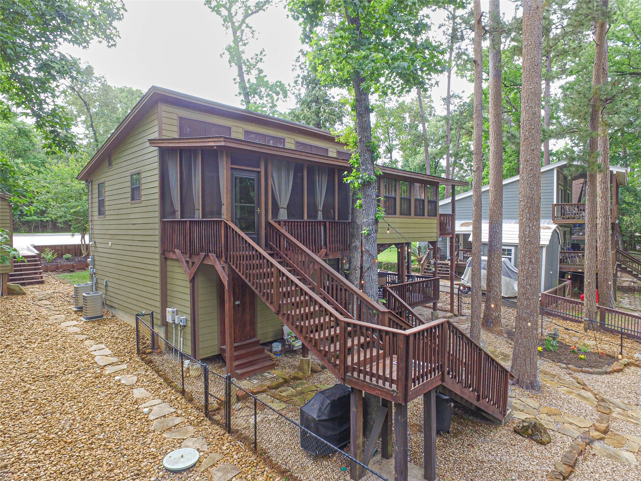 Everything is well maintained by the seller. The home was totally re-built in 2011. This view from the back shows the huge screen porch off of the kitchen and a view of the storage/workshop lower left.  On right the row of windows looks out from the open concept living area. Surrounded by nature!
