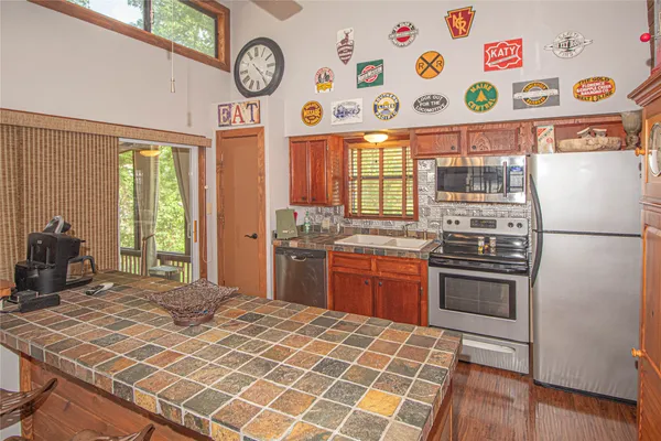 a kitchen with stainless steel appliances granite countertop a stove a sink and a refrigerator with wooden floor