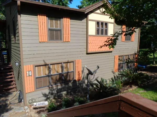a view of a house with a small yard plants and large tree