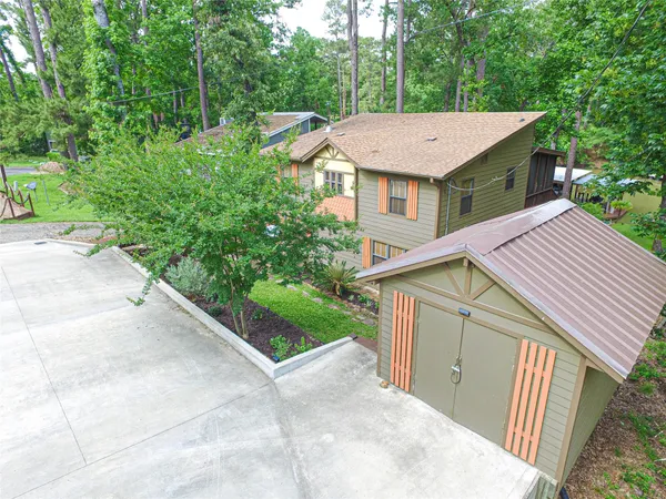 a view of a house with a yard plants and large tree