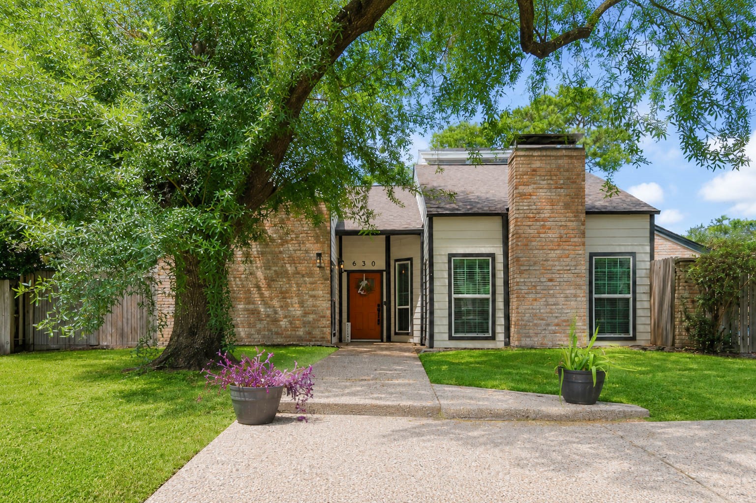 630 South Fry Road Katy, TX 77450 - Photo 1 of 48 Charming home featuring a welcoming brick façade, lush greenery, and a large, shady tree. The inviting walkway leads to a stylish front door, complemented by well-maintained landscaping.