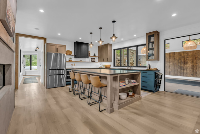 1766 West Tollgate Cyn Road Coalville, UT 84017 - Photo 8 of 59 Spacious kitchen featuring a large central island with integrated shelving, light wood-finish flooring, a stainless steel refrigerator, dark cabinetry, and multiple recessed light fixtures
