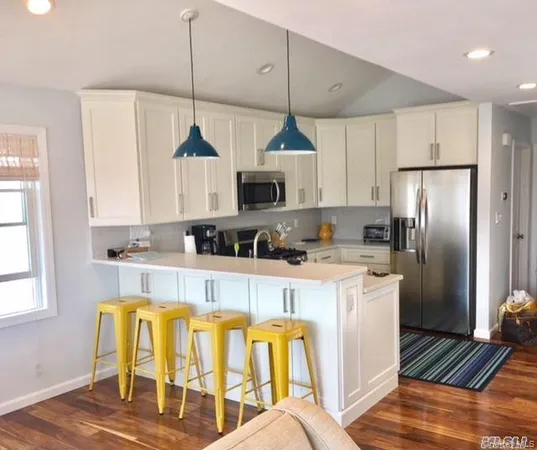 a kitchen with stainless steel appliances granite countertop a refrigerator a stove a sink dishwasher and a dining table with wooden floor
