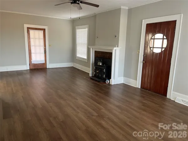 an empty room with wooden floor a fireplace and windows