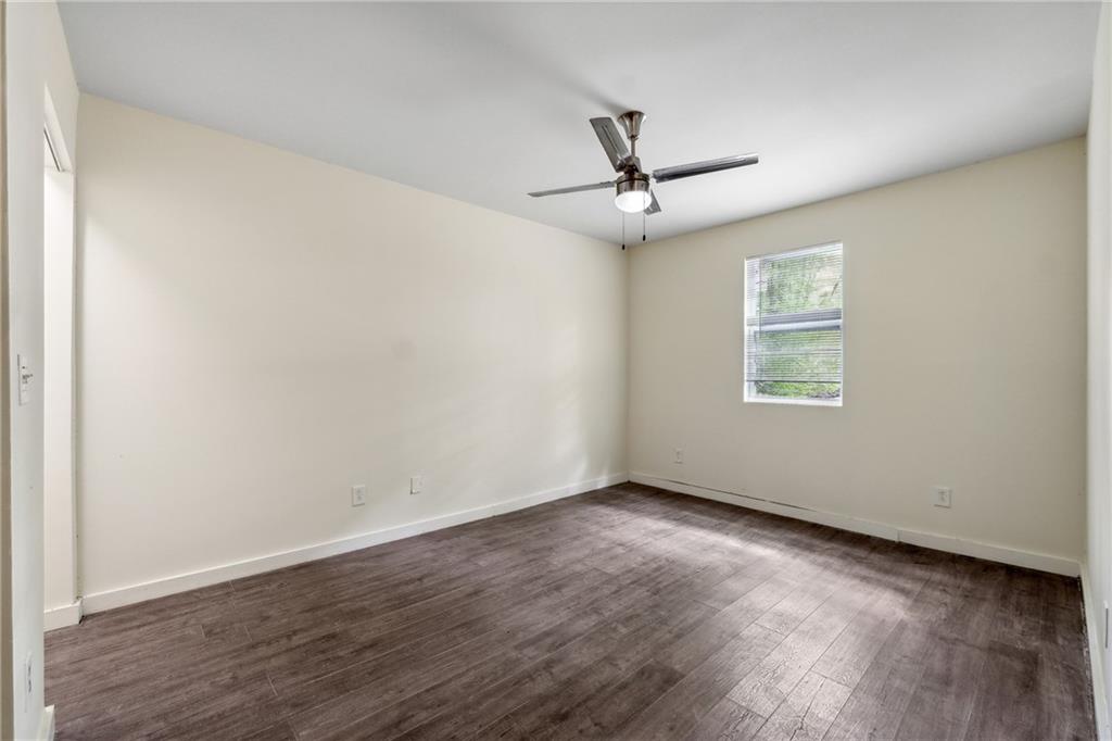 1303 North Druid Hills Road Brookhaven, GA 30319 - Photo 48 of 56 an empty room with wooden floor ceiling fan and windows