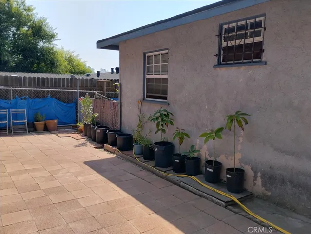 a view of a street with potted plants and brick wall