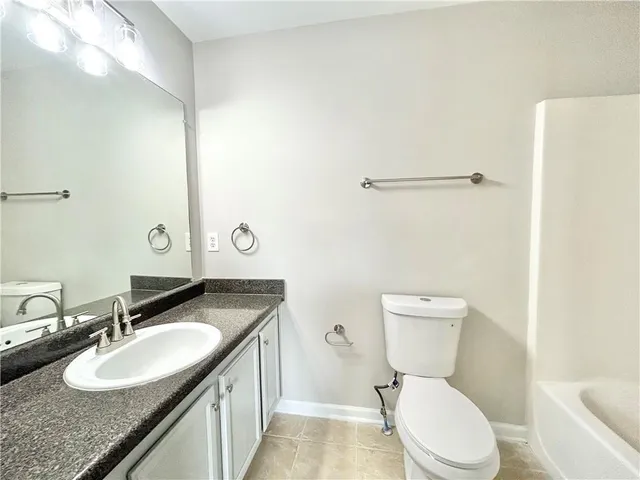 a bathroom with a granite countertop sink mirror vanity and a toilet