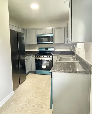 a kitchen with granite countertop a sink a stove a refrigerator and a sink