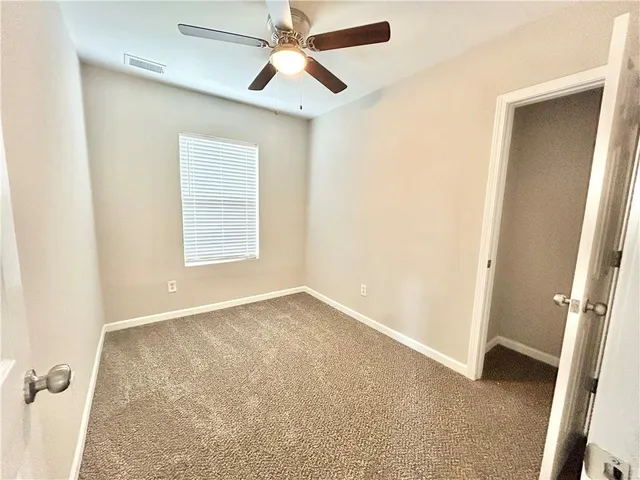 an empty room with windows and fan