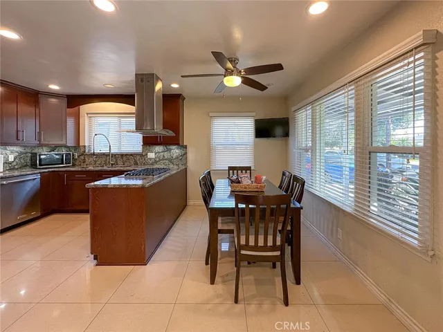 a kitchen with stainless steel appliances granite countertop wooden cabinets a dining table and chairs