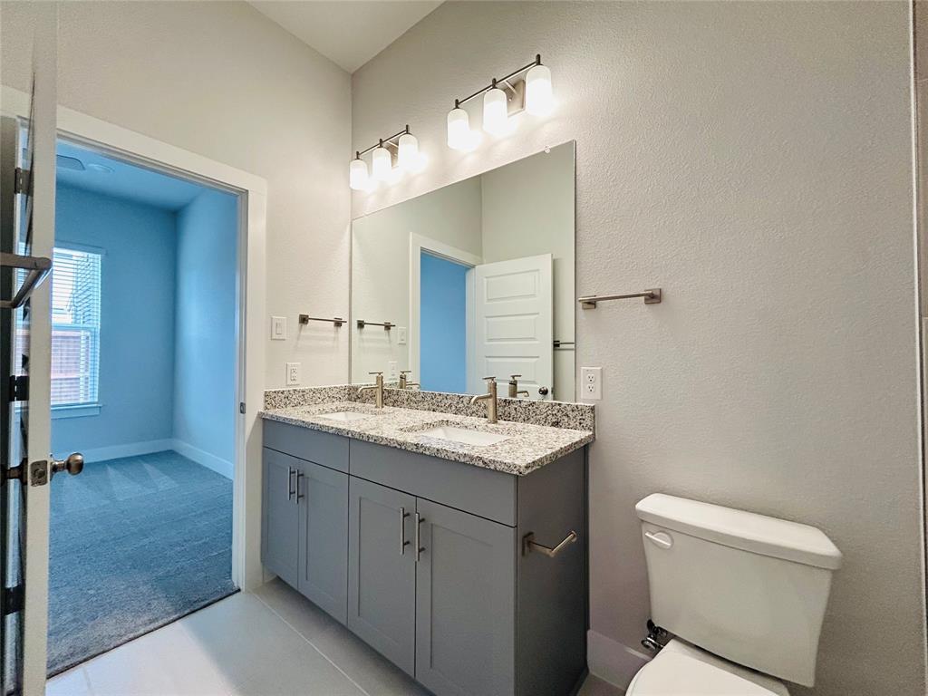 760 West Bedford Euless Road, Unit 200 Hurst, TX 76053 - Photo 11 of 39 a bathroom with a granite countertop sink a toilet and a mirror