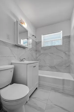 a bathroom with a granite countertop toilet a sink and bathtub