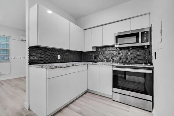 a kitchen with granite countertop white cabinets and stainless steel appliances
