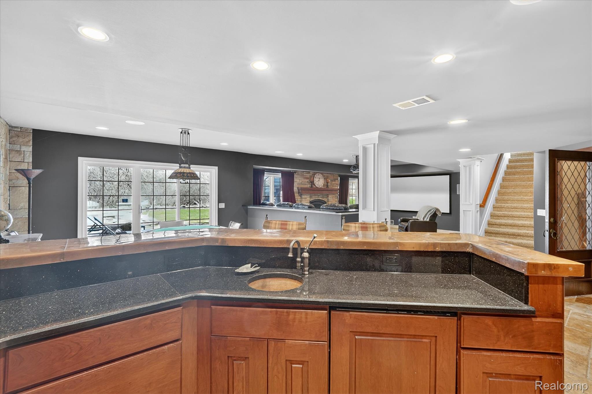 6932 Oakhurst Ridge Road Clarkston, MI 48348 - Photo 78 of 78 Kitchen featuring wood finish cabinets, decorative columns, open floor plan, hanging light fixtures, and dark stone counters