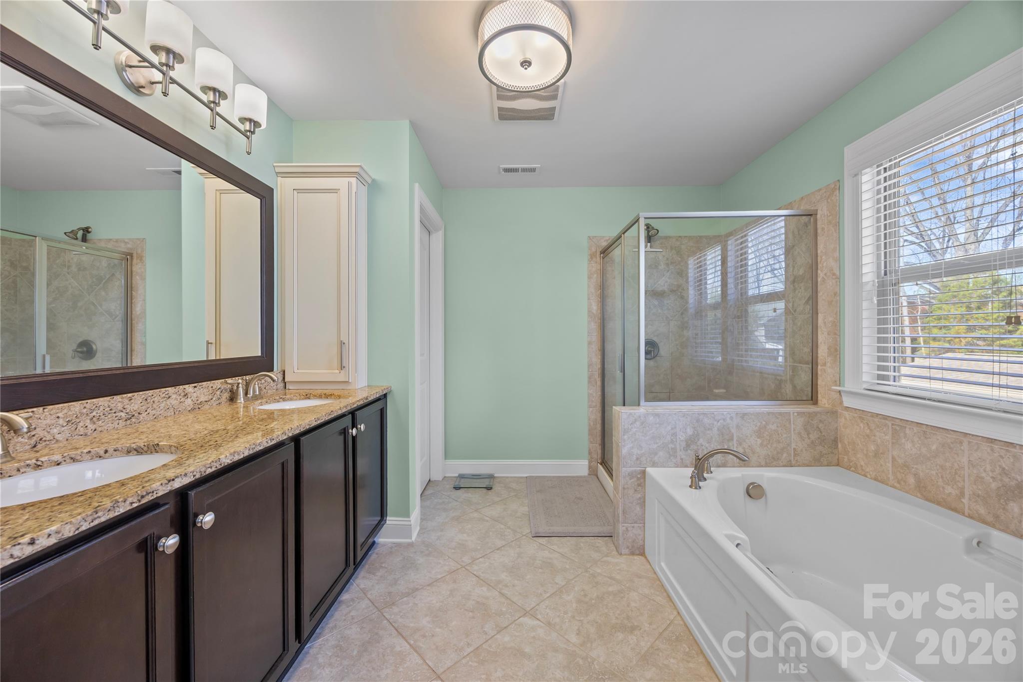 921 Rock Forest Way Fort Mill, SC 29707 - Photo 25 of 40 a bathroom with a granite countertop sink a large mirror and a bathtub with shower