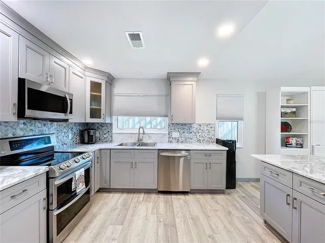 a large kitchen with granite countertop a sink and dishwasher a stove top oven with wooden floor