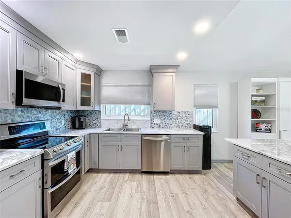a kitchen with stainless steel appliances kitchen island granite countertop a table chairs and a refrigerator