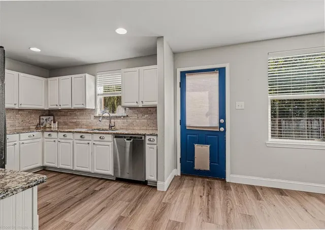 a kitchen with granite countertop a stove cabinets and wooden floor