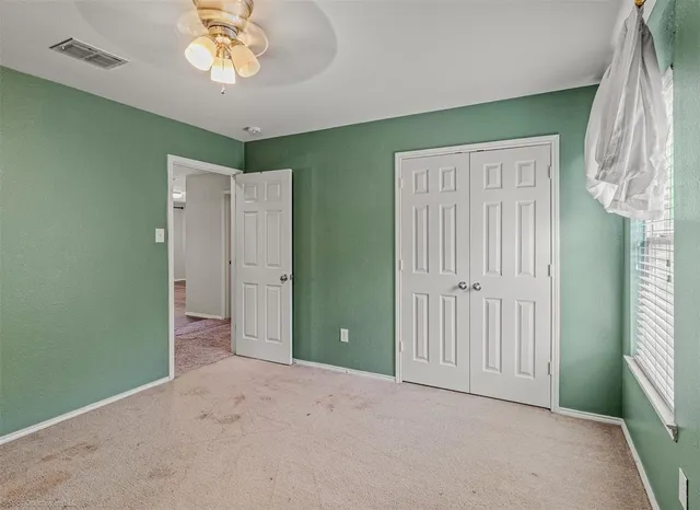an empty room with a fan and a window
