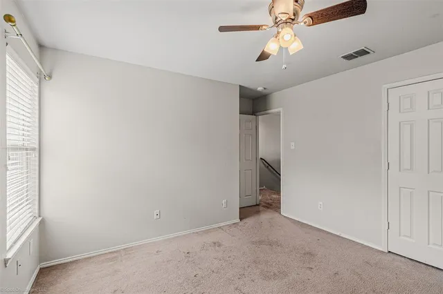an empty room with a ceiling fan and a window