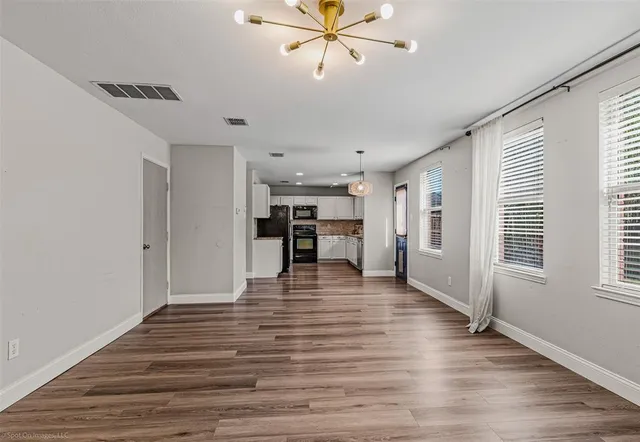 a view of an empty room with window and wooden floor