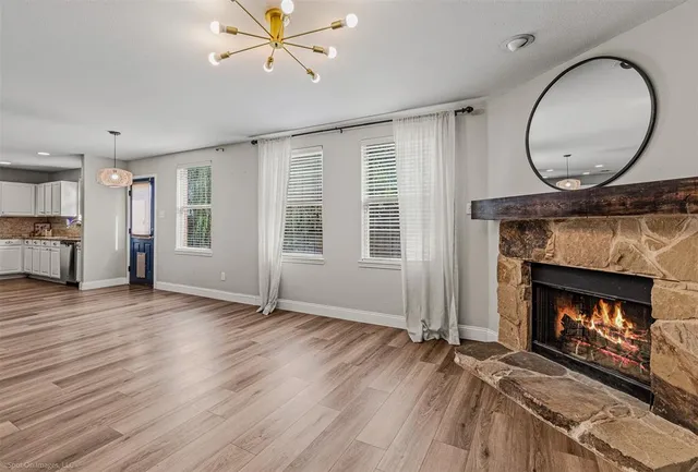 an empty room with wooden floor fireplace and windows
