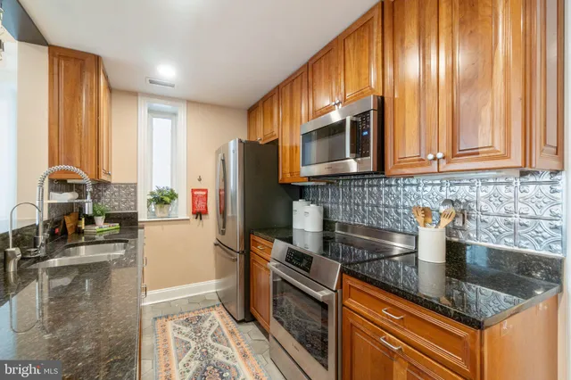 a kitchen with stainless steel appliances granite countertop a refrigerator a stove a sink and dishwasher